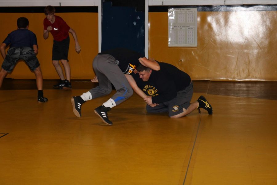 Wrestling coach James Patterson helps a player practice by grappling with him. Patterson has been coach since he got out of college.