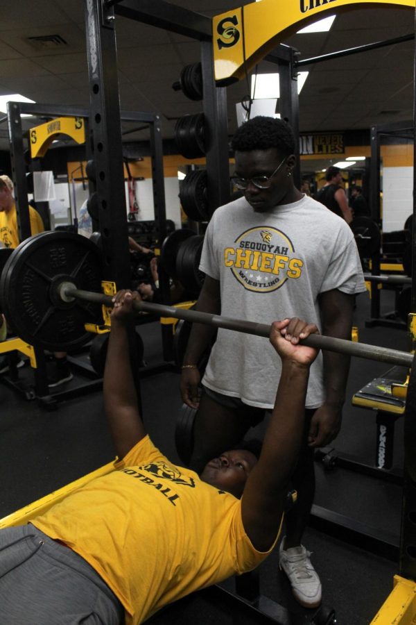 Football players bench press in the weight room. The team gets extra practice in the weight room before Friday night games.