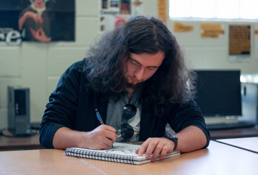 Senior Colin Schell works on a sketch at his desk. Schells biggest art piece took him over 50 hours to complete.